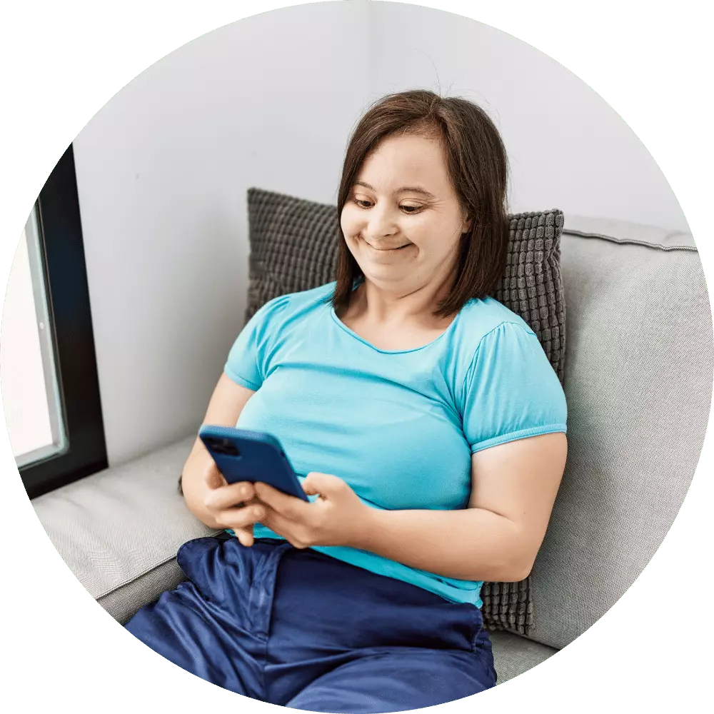 Happy girl with down syndrome sitting on couch making phone call