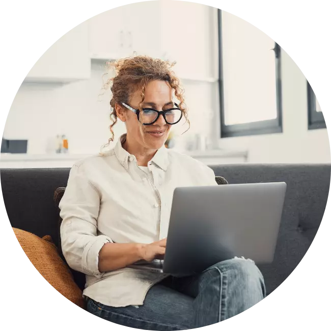 Happy professional woman sitting on couch using laptop to make NDIS referral